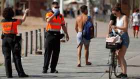 Agentes cívicos de Barcelona informan a una joven de la obligatoriedad de llevar mascarilla / EFE - TONI ALBIR