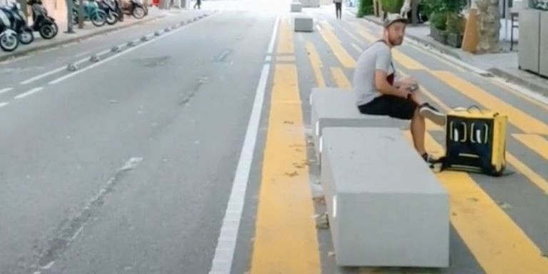 Un hombre sentado en un bloque de hormigón en Consell de Cent 