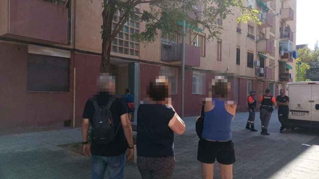 Un grupo de vecinos y empleados de una empresa de seguridad, delante del edificio afectado