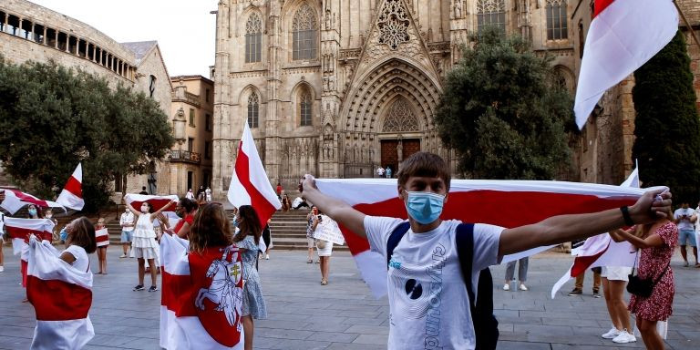 Un manifestante sujeta la bandera bielorrusa en la plaza de la Catedral de Barcelona / EFE