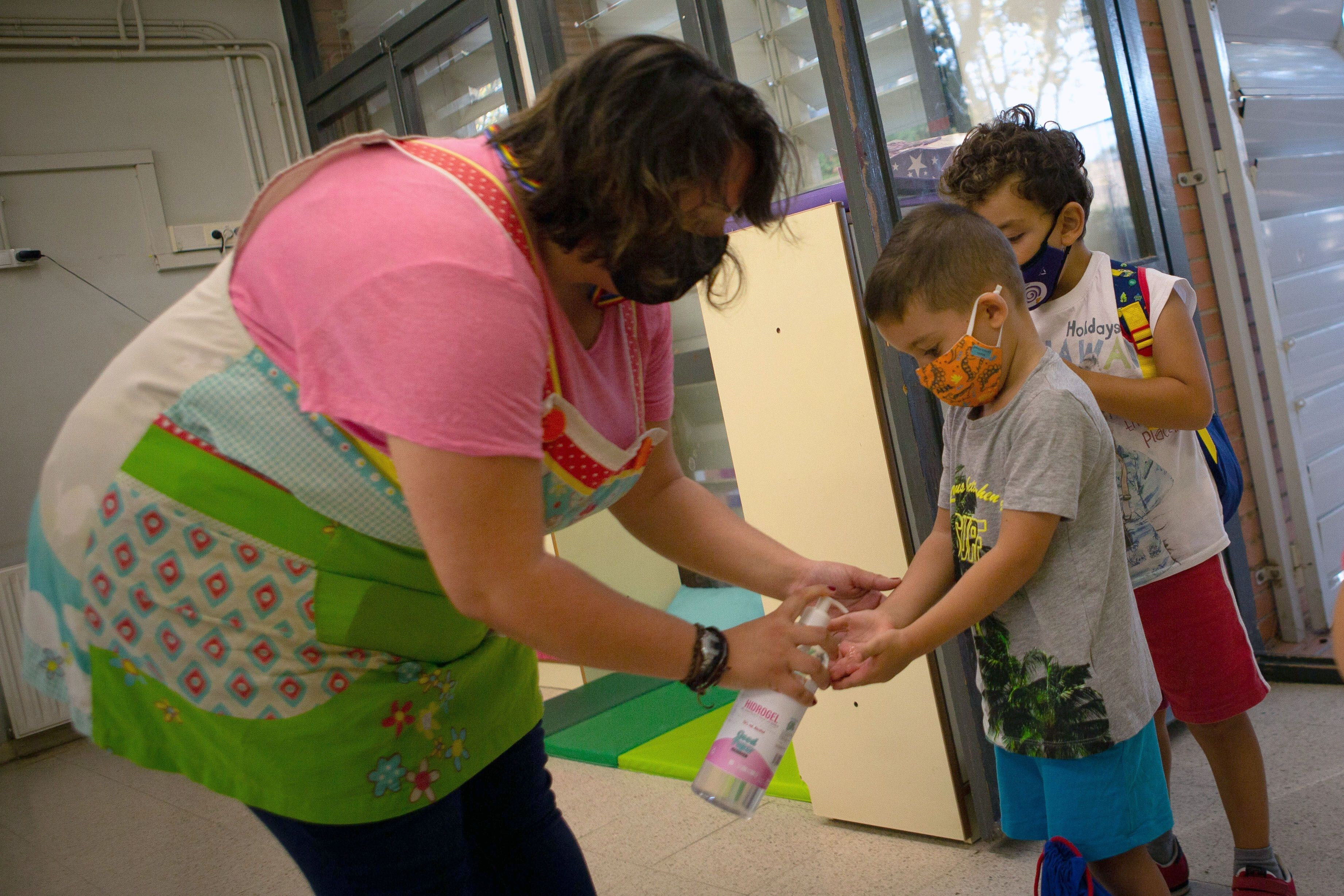 Una docente de la Escuela Catalonia de Barcelona aplica gel hidroalcohólico a sus alumnos al entrar al recinto / EFE