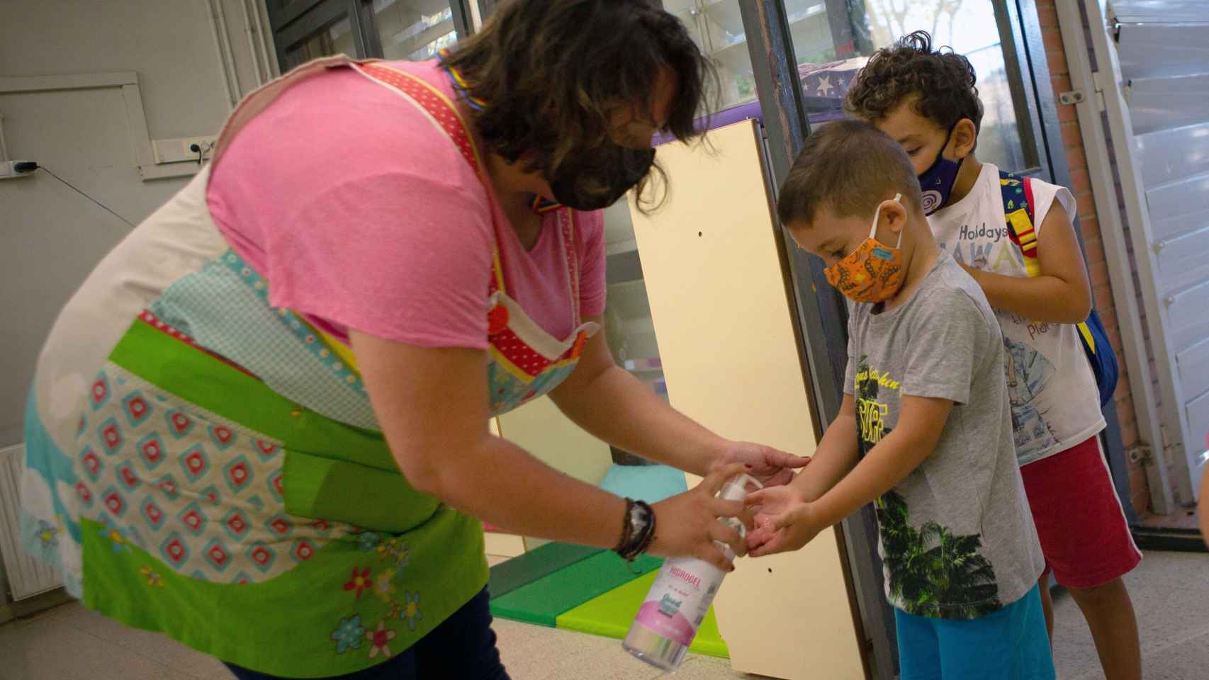 Una docente de la Escuela Catalonia de Barcelona aplica gel hidroalcohólico a sus alumnos al entrar al recinto / EFE