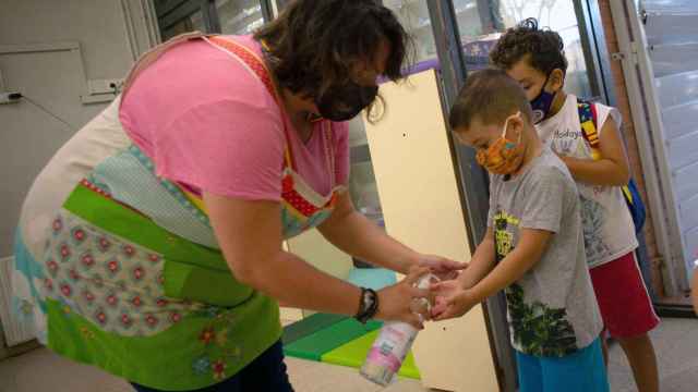 Una docente de la Escuela Catalonia de Barcelona aplica gel hidroalcohólico a sus alumnos al entrar al recinto / EFE