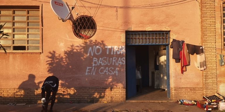 Un hombre se lava enfrente de la entrada del inmueble okupado / G.A