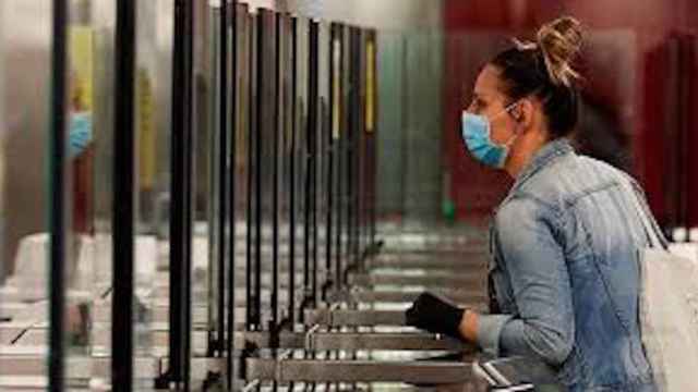 Una mujer entra al metro de Barcelona con mascarilla y guantes puestos / EFE