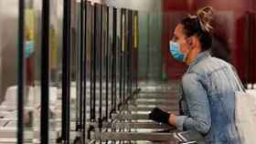 Una mujer entra al metro de Barcelona con mascarilla y guantes puestos / EFE