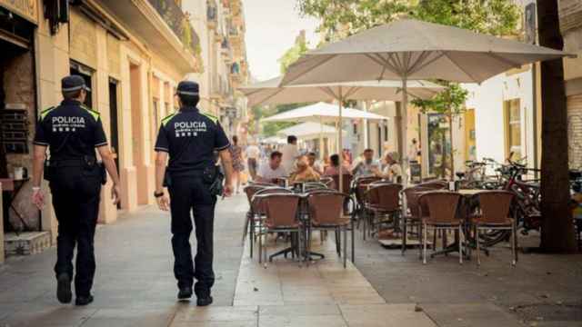 Dos guardia urbanos pasean por delante de una terraza en Barcelona / GUARDIA URBANA