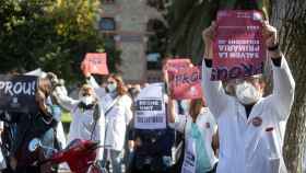 Decenas de médicos de la atención primaria pública protestan con carteles de los destinos a los que tienen que emigrar ante la sede del departamento de Salud en Barcelona /