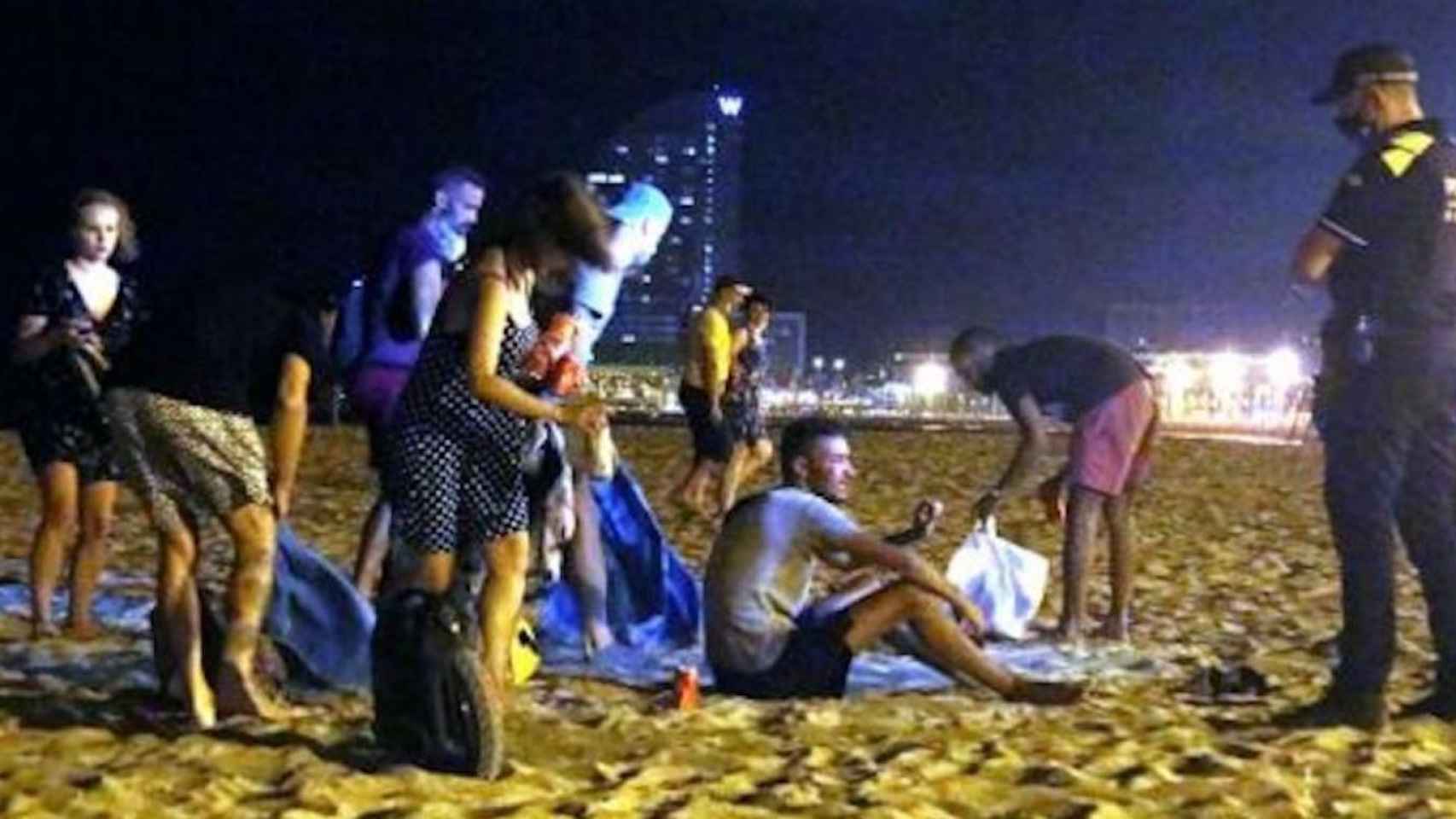 Agentes de la Guardia Urbana junto a unos jóvenes que practicaban el botellón en la playa, este verano / EP