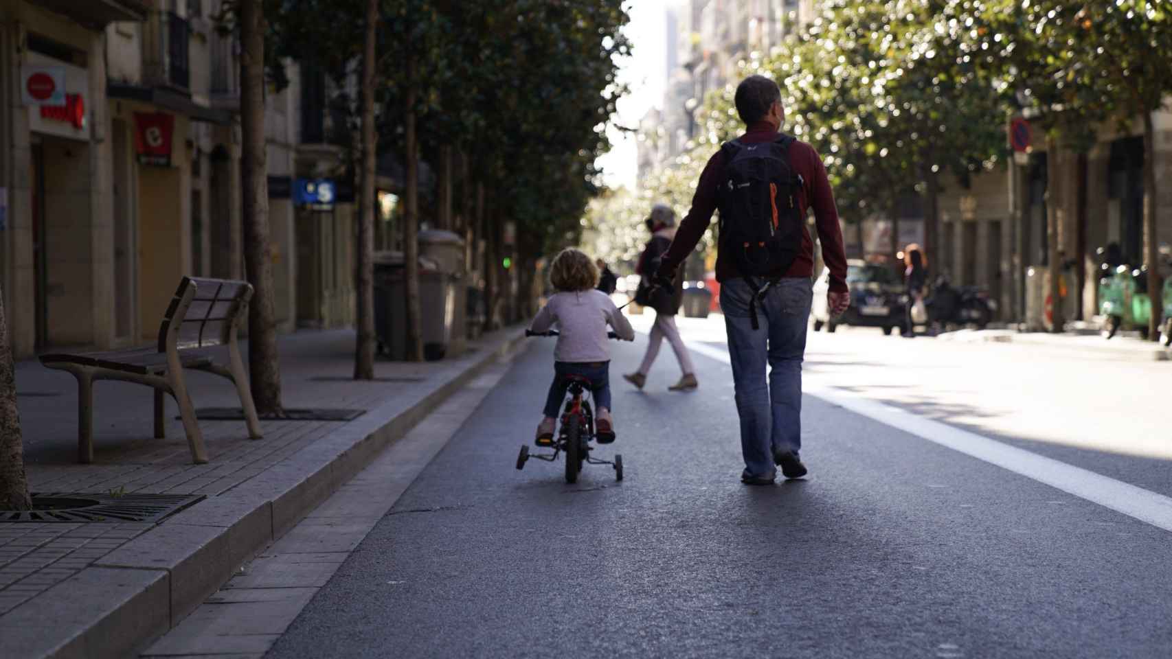 Un hombre pasea con una niña en la calle Gran de Gràcia / AYUNTAMIENTO DE BARCELONA