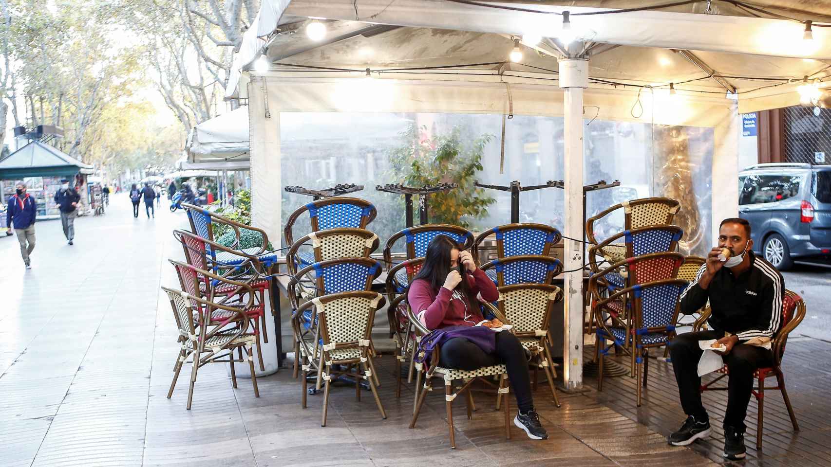 Dos personas desayunan en la terraza de un bar cerrado de las Ramblas de Barcelona / EFE - Quique García