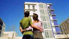 Una pareja joven frente a unas viviendas de nueva construcción