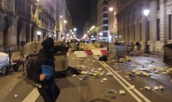 Un actor lanza un objeto entre contenedores ayer en Barcelona / METRÓPOLI ABIERTA