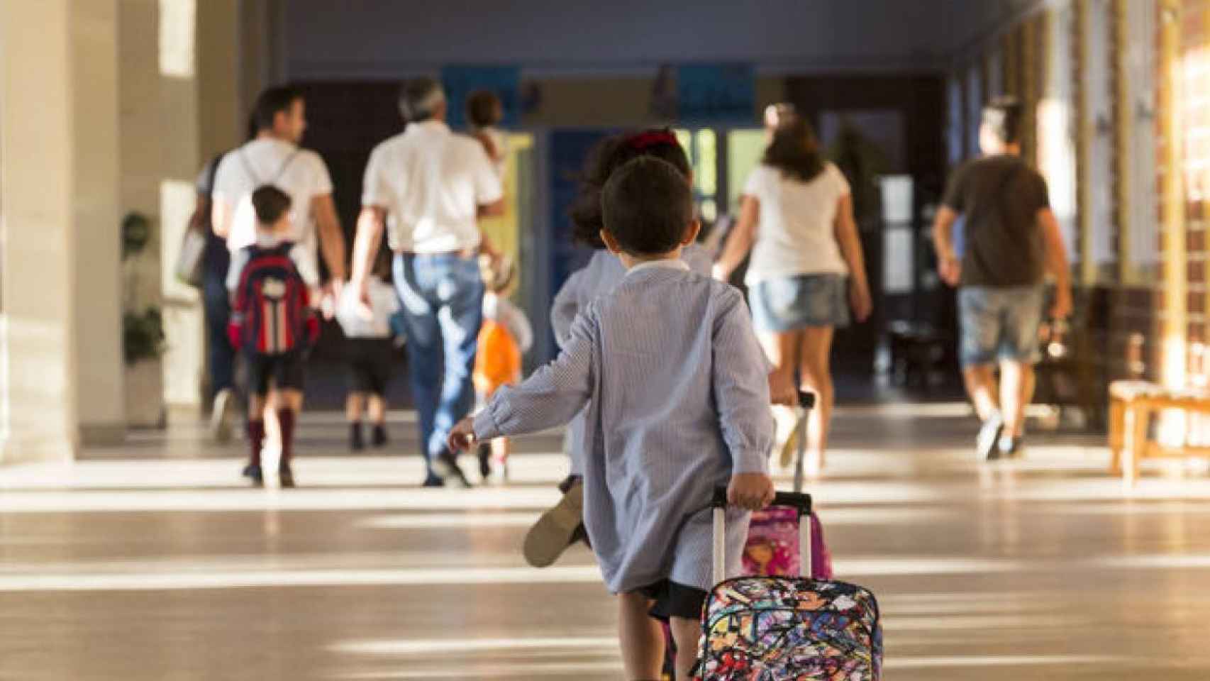 Varios estudiantes de infantil entrando con sus padres en un colegio / EFE