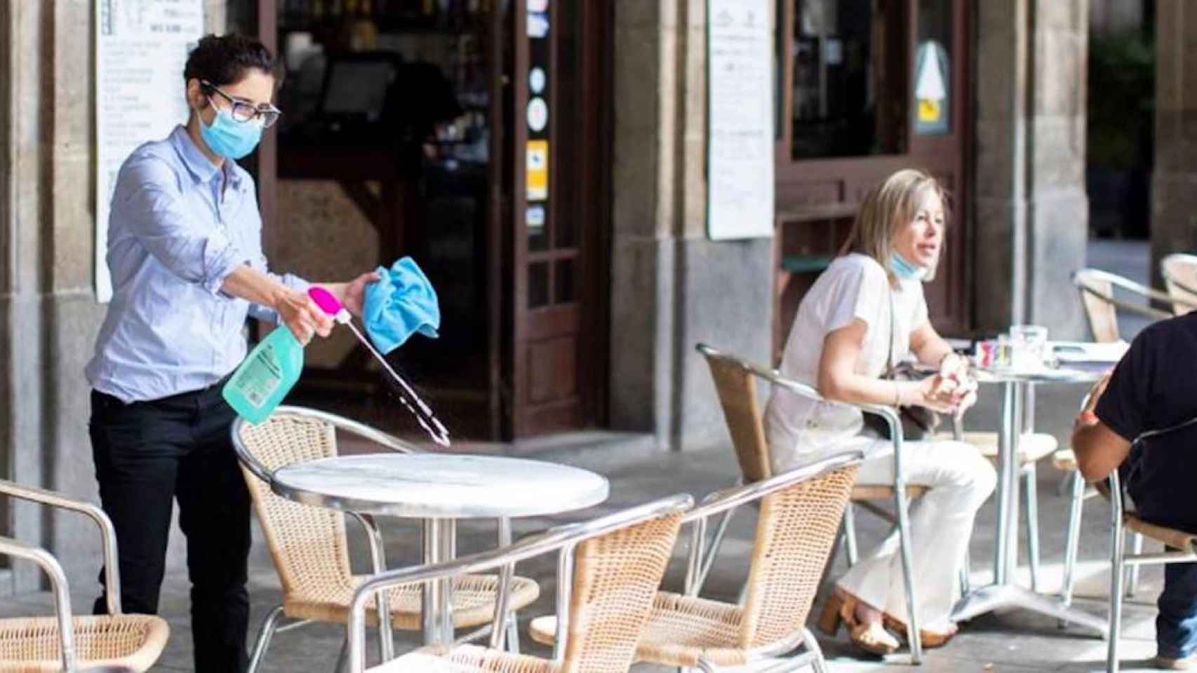 Una restauradora desinfecta una mesa en su negocio de la plaza Reial de Barcelona / EFE