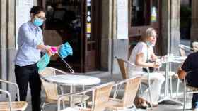 Una restauradora desinfecta una mesa en su negocio de la plaza Reial de Barcelona / EFE