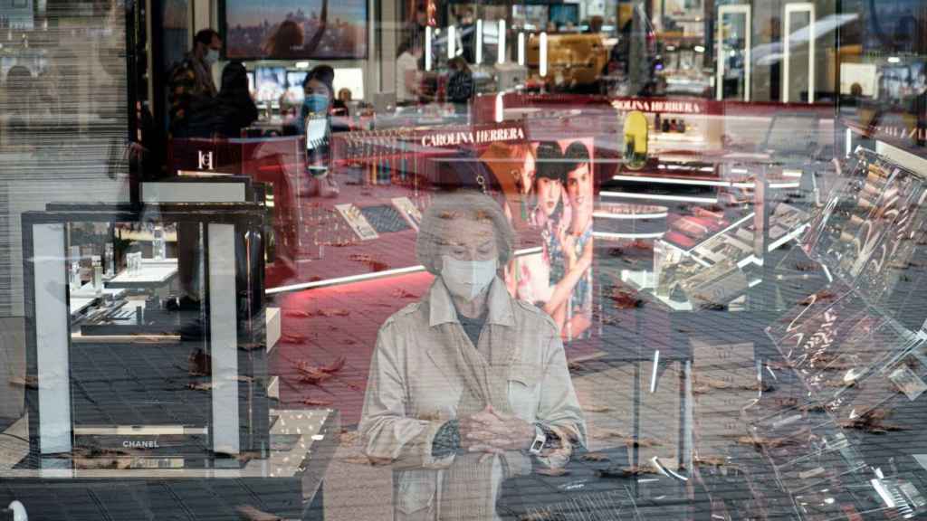 Una mujer, con la mirada perdida, observa a través de los cristales durante sus compras de Black Friday en Barcelona / PABLO MIRANZO