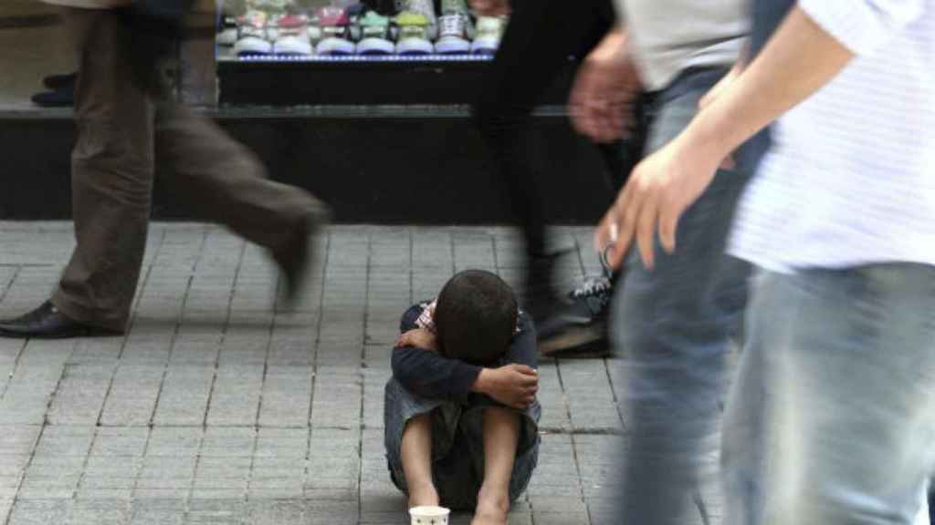 Un niño pequeño pide limosna en una calle / EFE