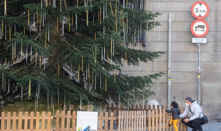 Un hombre con un niño en el árbol de Navidad de la plaza de Sant Jaume de Barcelona / EFE – Marta Pérez