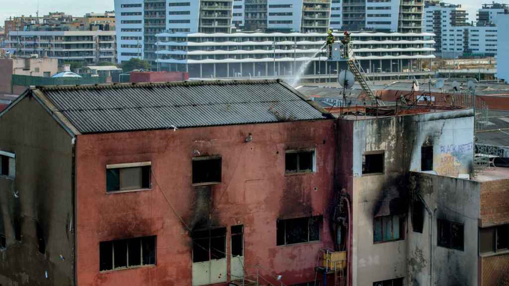 Los bomberos realizan su trabajo para intentar acabar de sofocar el incendio de la nave incendiada, ya controlada / EFE - Enric Fontcuberta