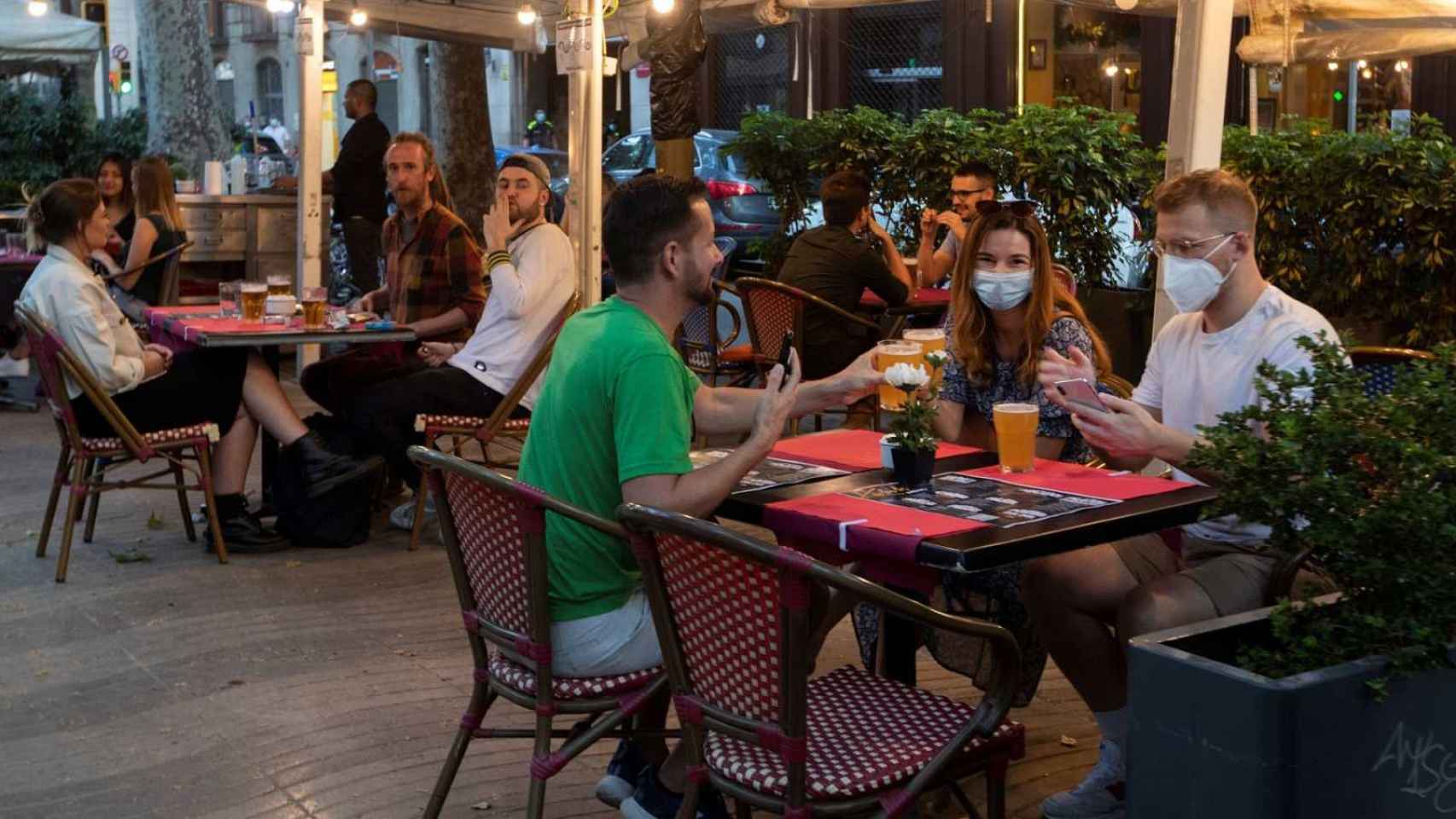 Varios comensales cubiertos con mascarilla en una terraza / EFE