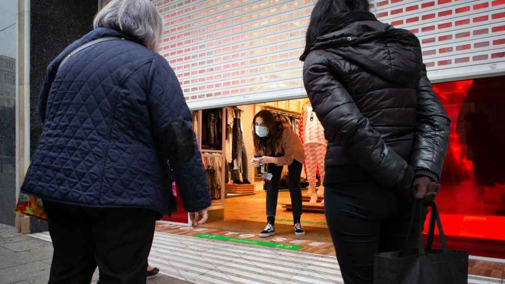 Dos clientas observan el interior una tienda medio cerrada