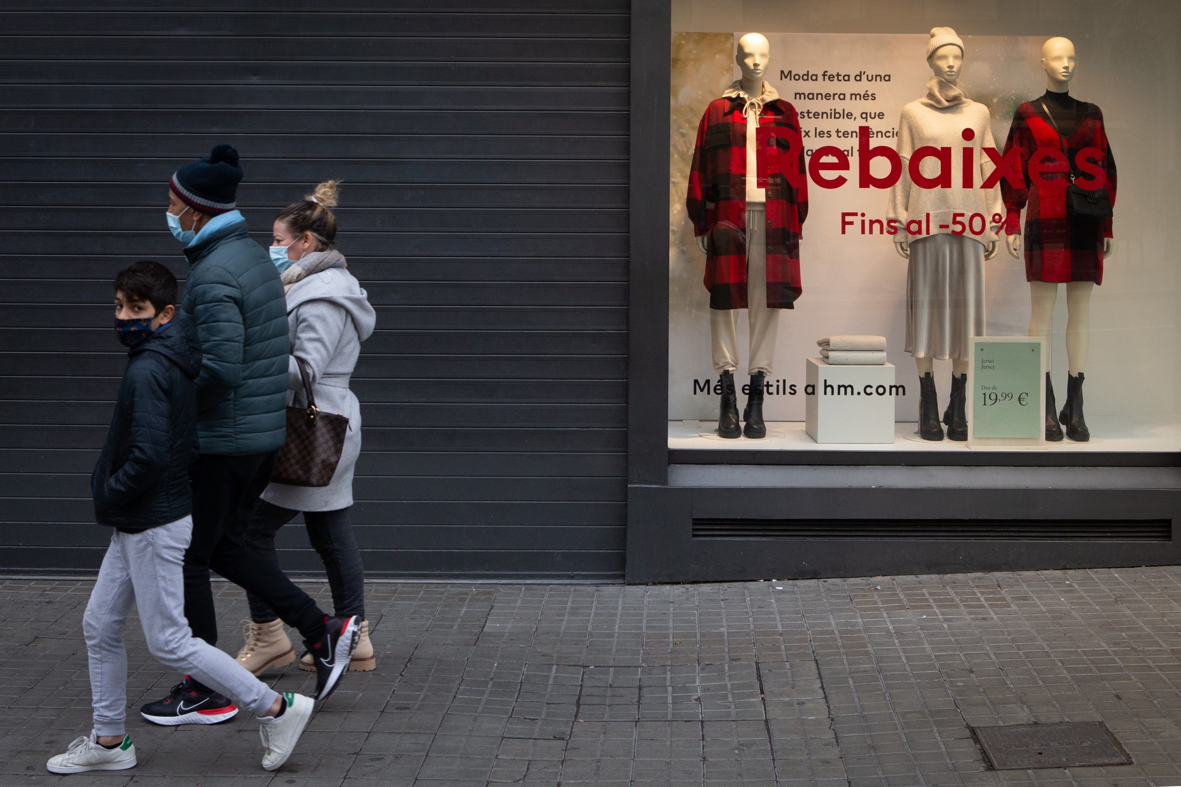 Una familia pasa por delante de una tienda cerrada durante el gélido arranque de las rebajas de 2020 en Barcelona / EFE