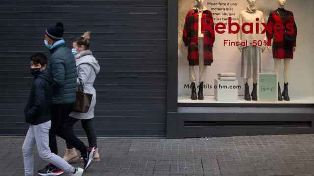 Una familia pasa por delante de una tienda cerrada durante el gélido arranque de las rebajas en Barcelona / EFE