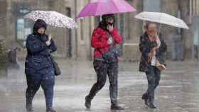 Tres personas cubiertas con un paraguas durante una jornada de lluvias en Barcelona / EFE