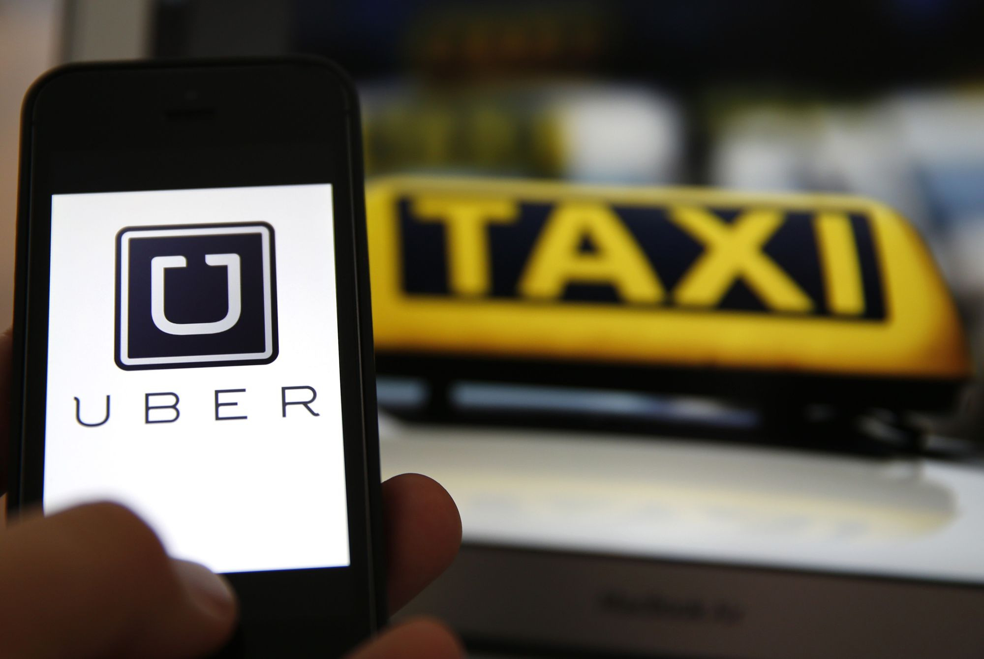 Un usuario usando la plataforma Uber y delante, un taxi en marcha / ARCHIVO