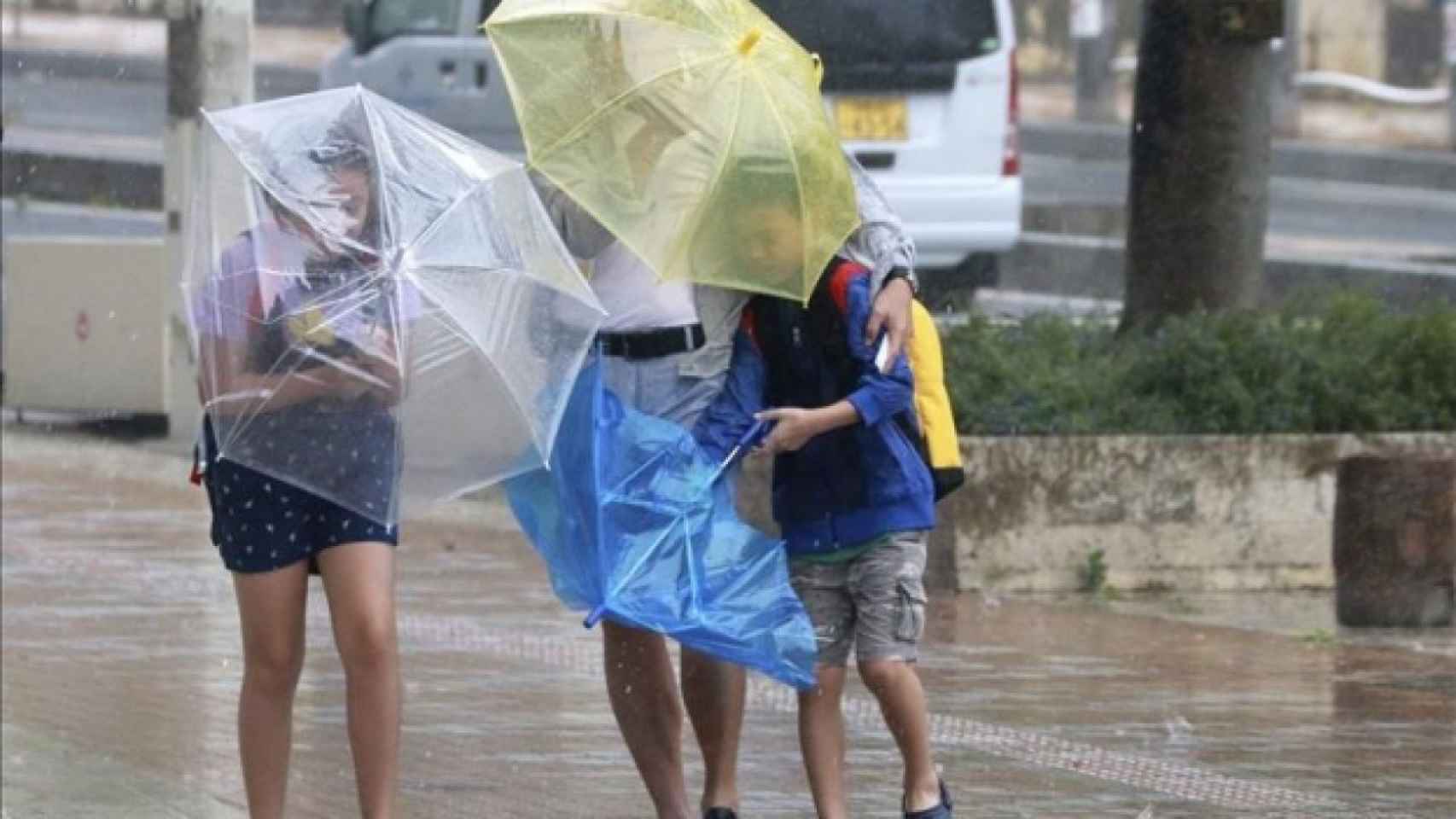 Varios viandantes luchan contra los fuertes vientos y la lluvia / EFE