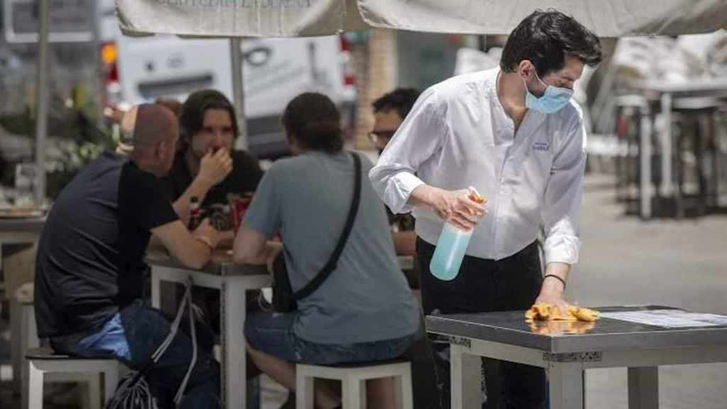 Un camarero limpia una mesa con la mascarilla puesta / EUROPA PRESS