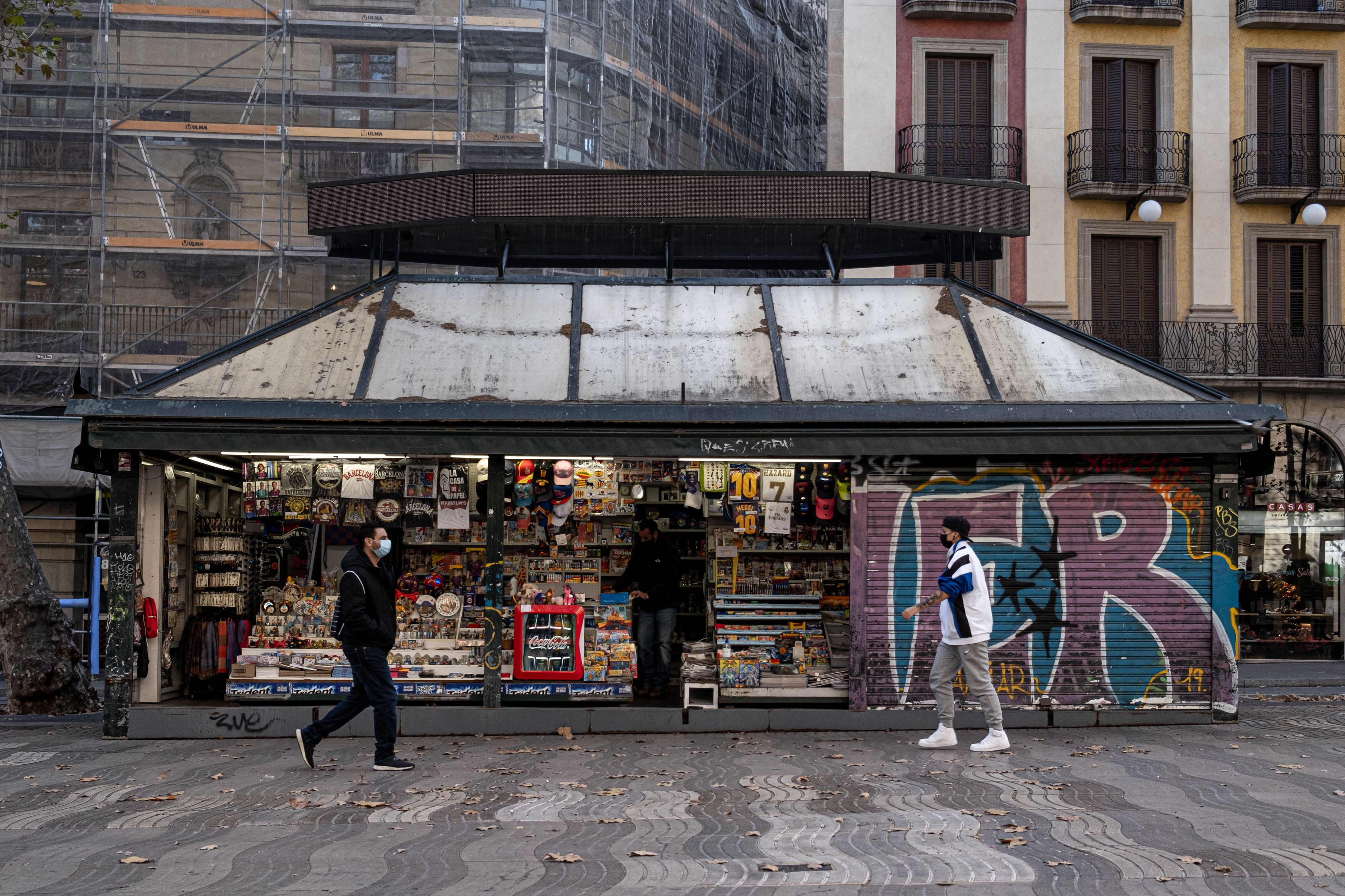 Dos personas pasean por delante de un kiosko de La Rambla, sin turistas y muy poca gente / PABLO MIRANZO