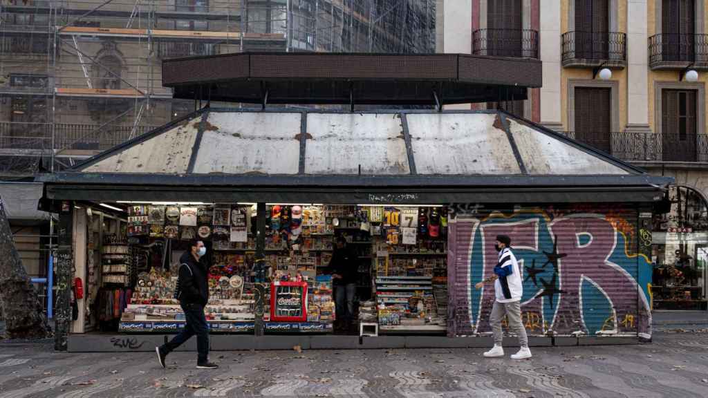 Personas caminan por delante los icónicos quioscos de las ramblas