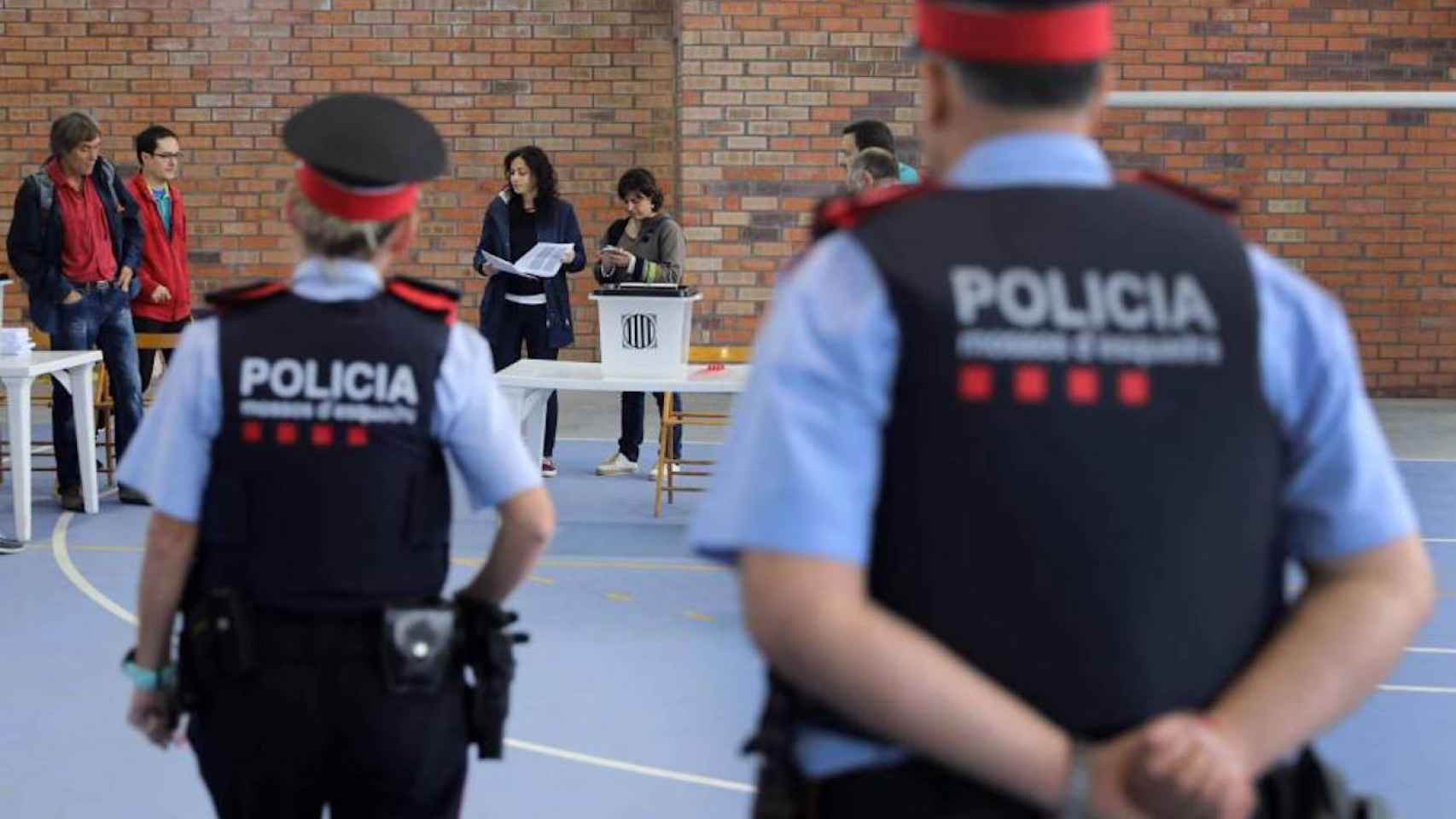 Una pareja de los Mossos en un colegio electoral / AFP - CESAR MANSO