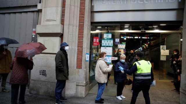 Varias personas hacen cola para votar en el colegio electoral situado en el Mercat del Ninot en Barcelona este domingo cuando se celebran las elecciones regionales / EFE - Toni