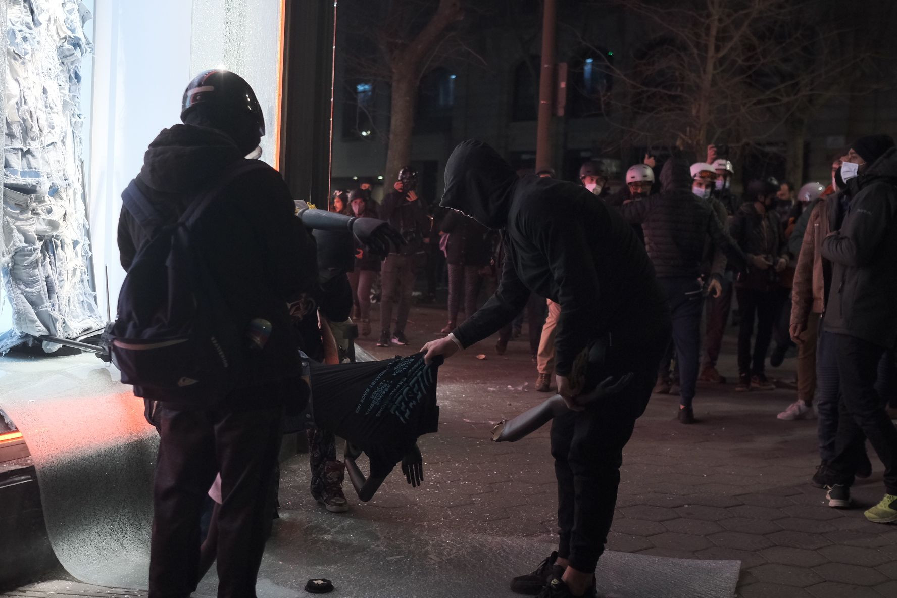 Unos jóvenes encapuchados rompen una prenda de ropa de una tienda saqueada / PABO MIRANZO - MA