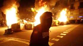 Un manifestante pasa por delante de barricadas ardiendo durante la cuarta noche de altercados por Hasél en Barcelona / EFE