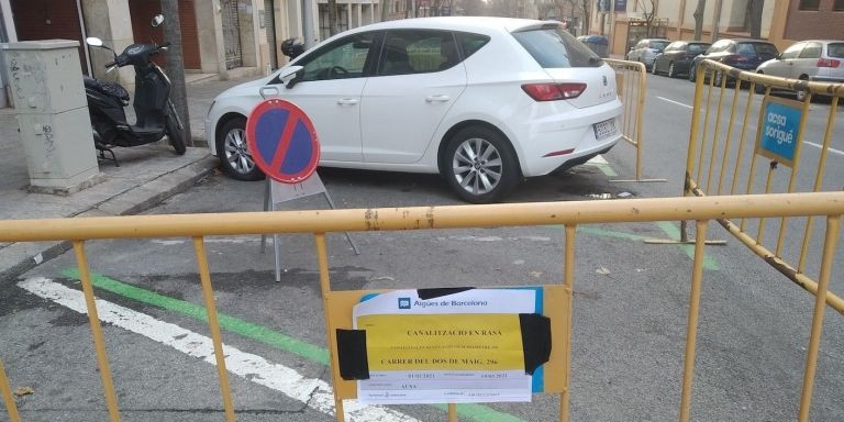 Una coche encerrado por vallas junto a una señal de prohibido estacionar / MA - JORDI SUBIRANA 