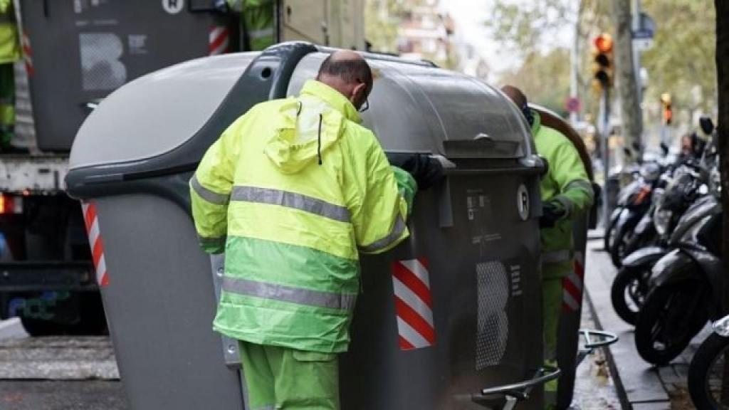 Dos operarios trasladan un contenedor en Barcelona