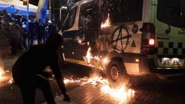 Un radical junto a la furgoneta incendiada de la Guardia Urbana, este sábado en Barcelona / PABLO MIRANZO