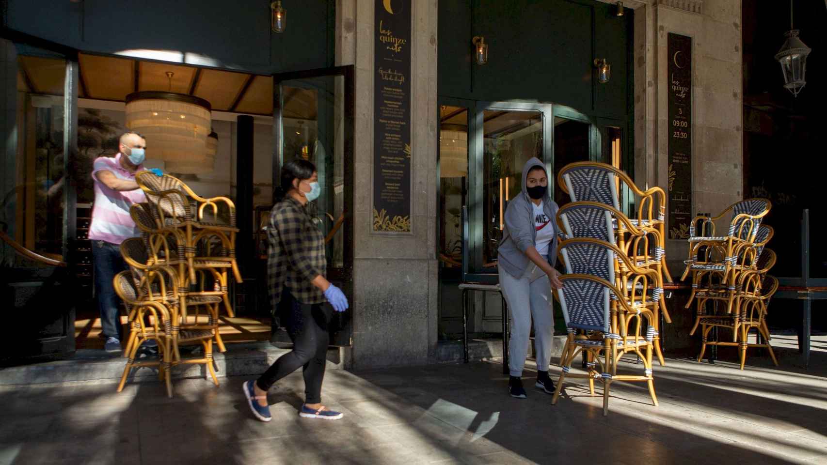 Dos trabajadores recogen la terraza de un bar del centro de Barcelona, afectado por las restricciones sanitarias del coronavirus /EFE/Enric Fontcuberta