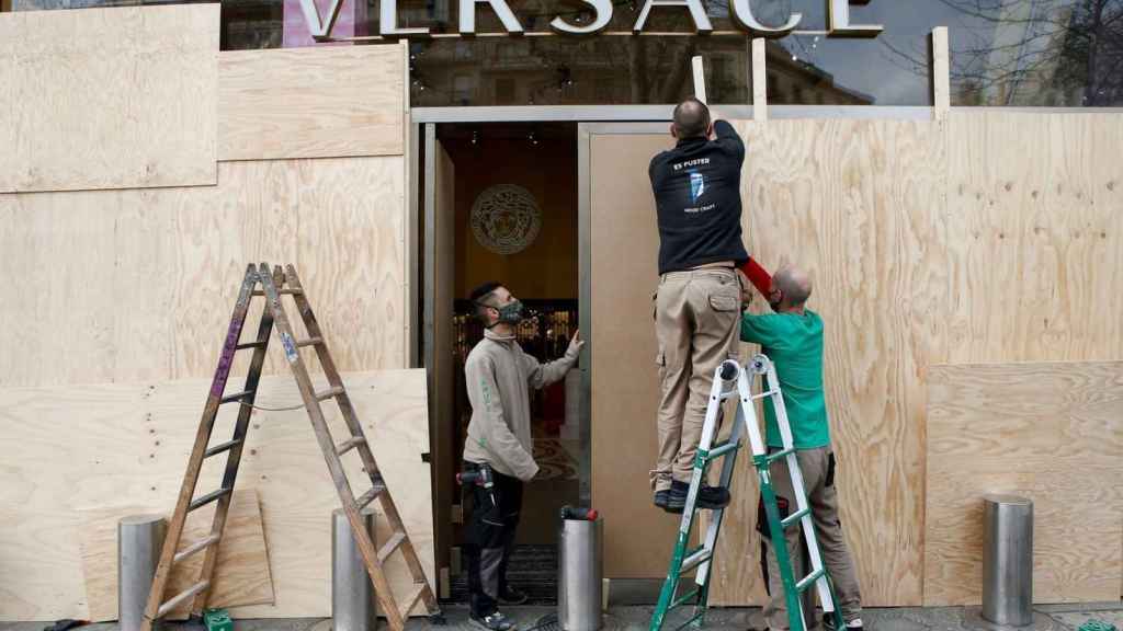Operarios arreglando los daños producidos por los disturbios y blindando un comercio de lujo del paseo de Gràcia / EFE