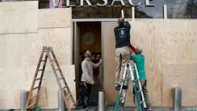 Operarios arreglando los daños producidos por los disturbios y blindando un comercio de lujo del paseo de Gràcia / EFE