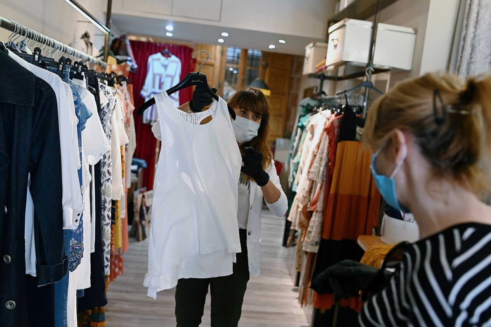 Una dependienta de una tienda de ropa muestra una prenda a una clienta / EFE