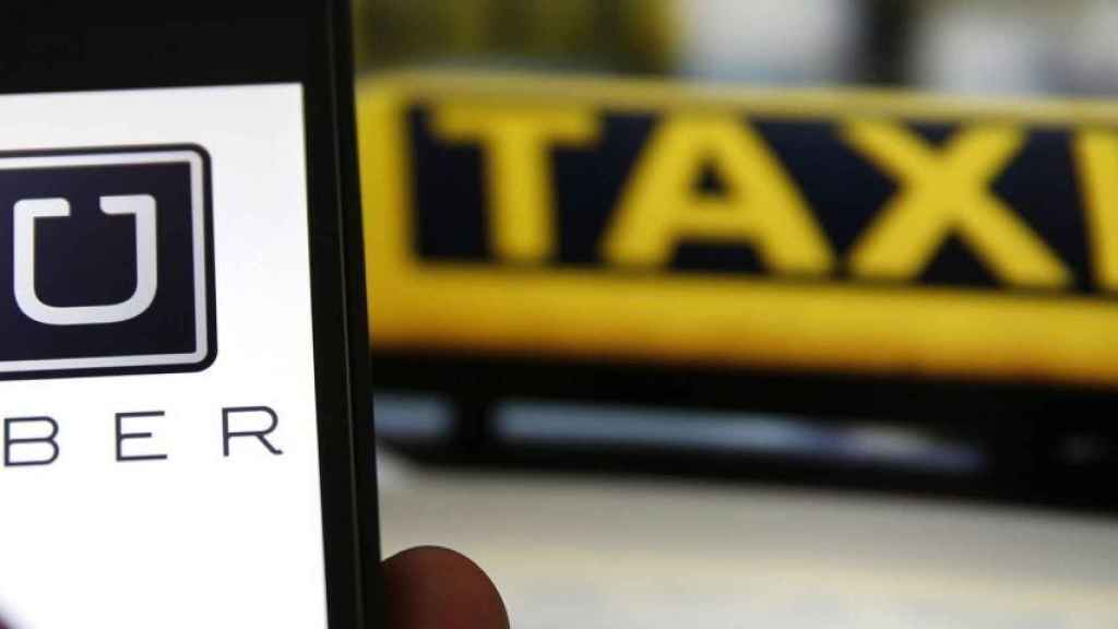 Un usuario usando la plataforma Uber y delante, un taxi en marcha / ARCHIVO