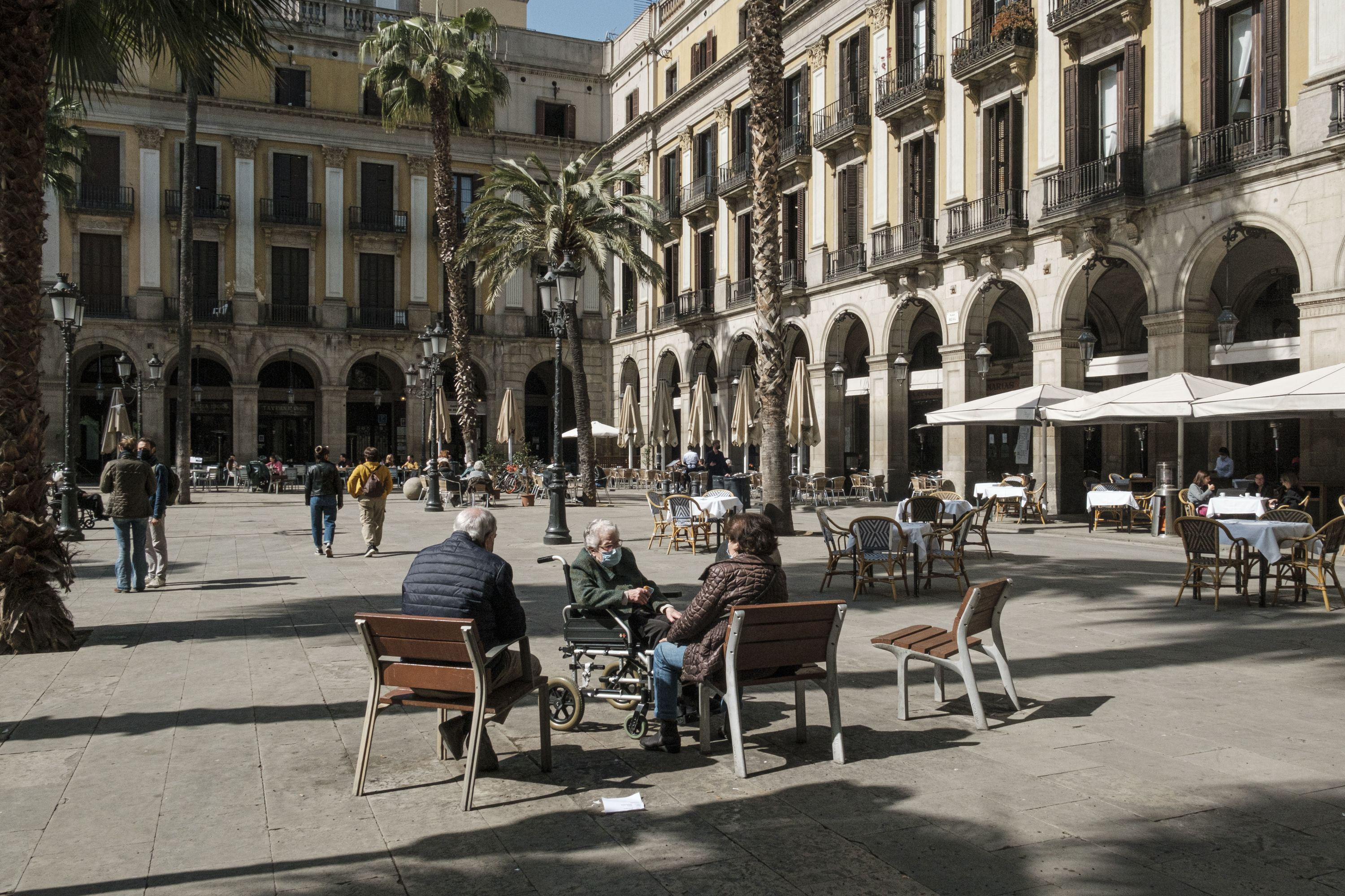 Ancianos toman el sol a medio día en la Plaza Reial / PABLO MIRANZO (MA)