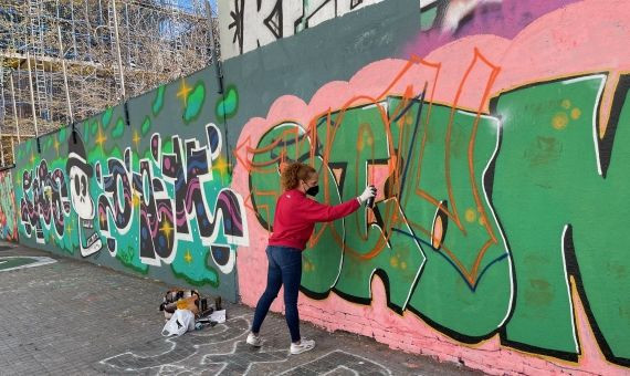 Una chica pintando un grafiti textual en la calle de Venezuela / A.F.