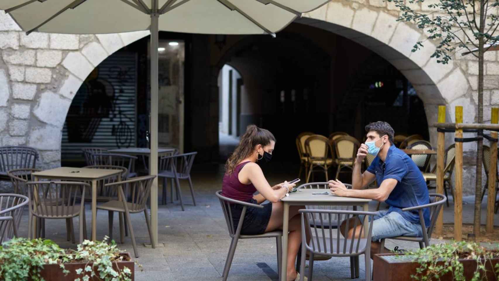 Dos personas sentadas en la  terraza de un bar en una imagen de archivo