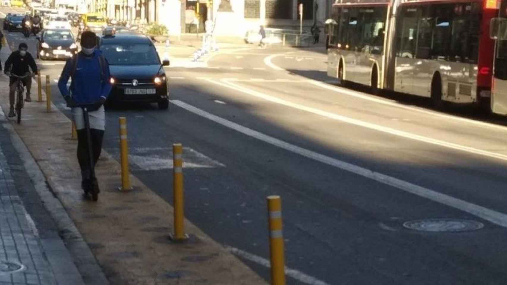 Un patinete y una bici en el carril peatonal de vía Laietana de Barcelona con separadores para proteger al peatón / MA - JORDI SUBIRANA